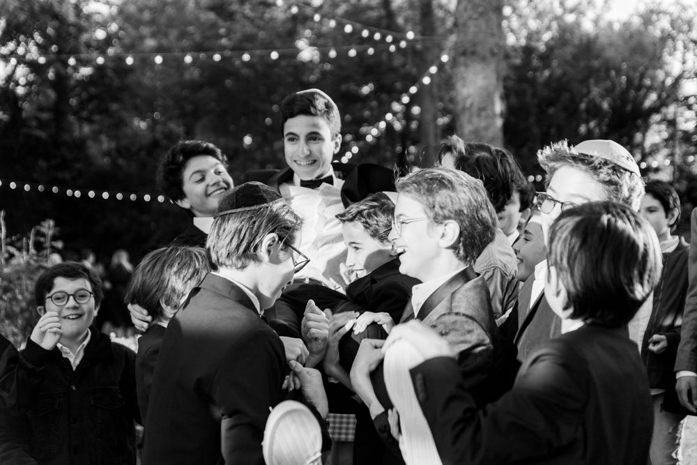 Black and white candid celebration photo with festive string lights. bar mitsva