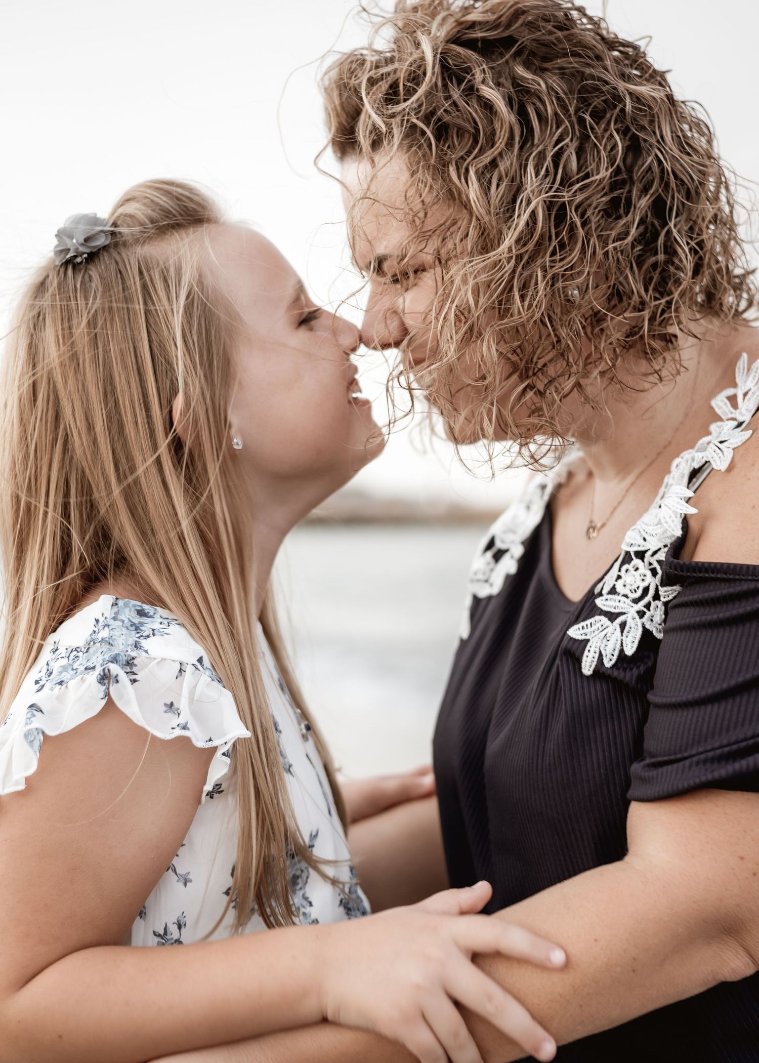 A touching nose-to-nose moment captured between mom and daughter in soft natural light.
