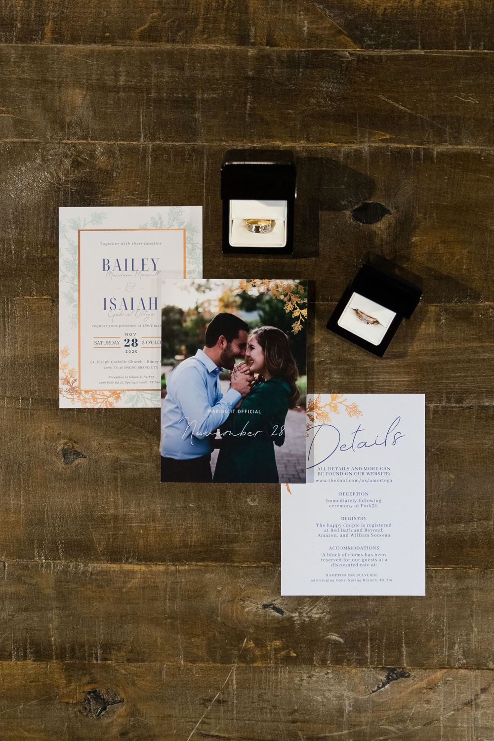 Wedding invitation suite with floral design and details cards laid on a rustic wooden surface.