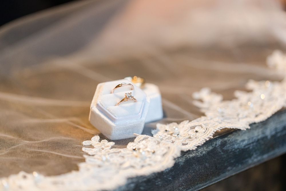 Wedding rings resting on a small white hexagonal box with delicate lace details.