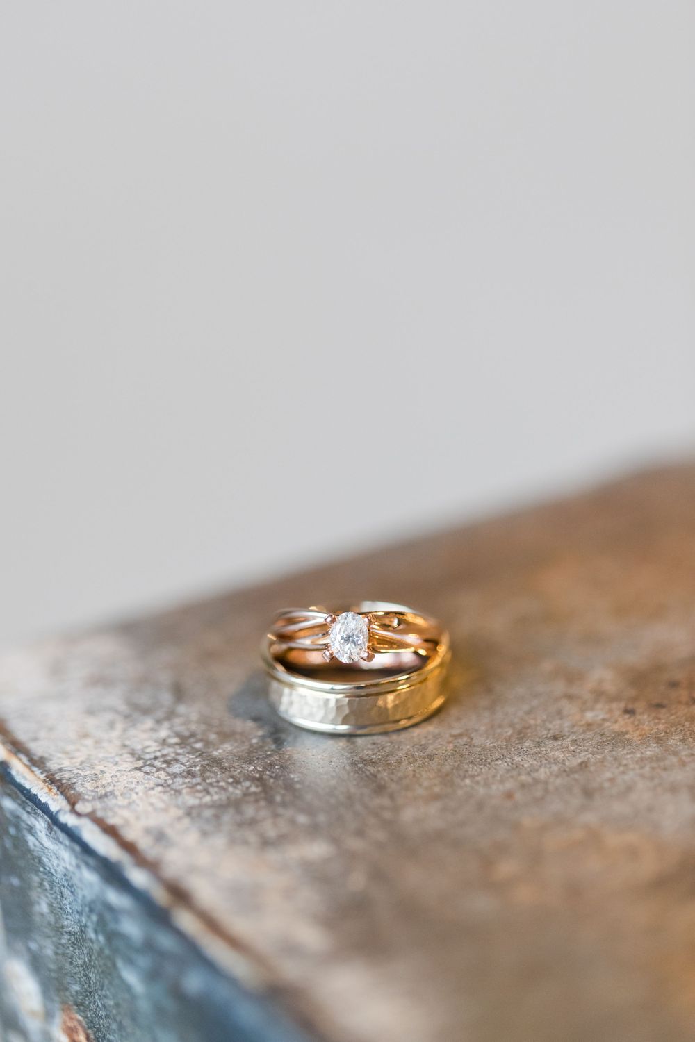 Two wedding bands with diamond details resting on a textured metallic surface.