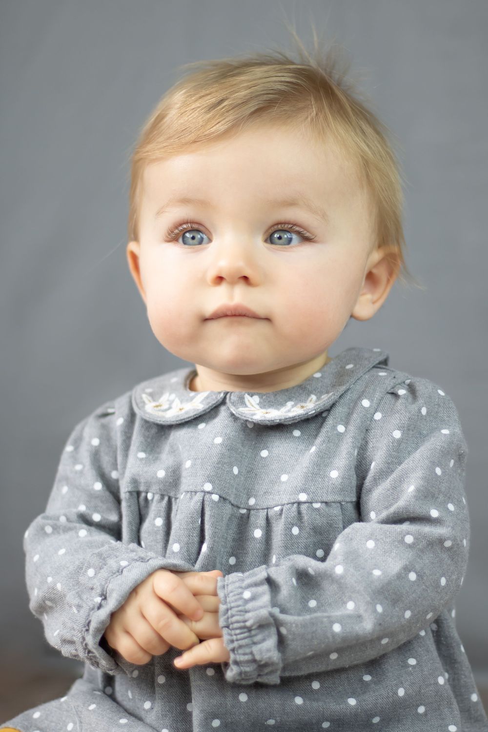 posed photography sitter session of girl in grey spotty dress