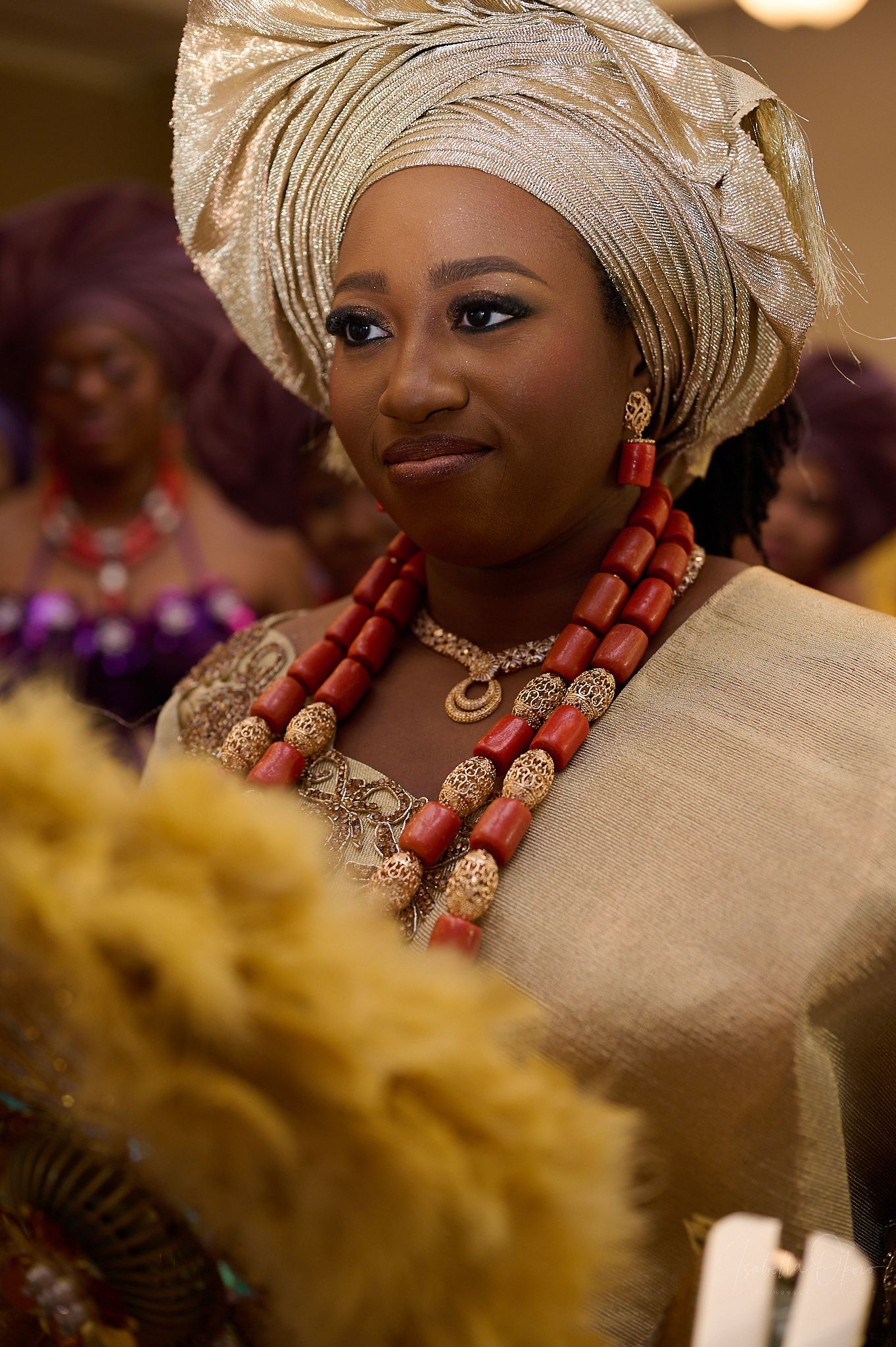Traditional African wedding attire featuring coral beads and elegant cream gele headwrap.