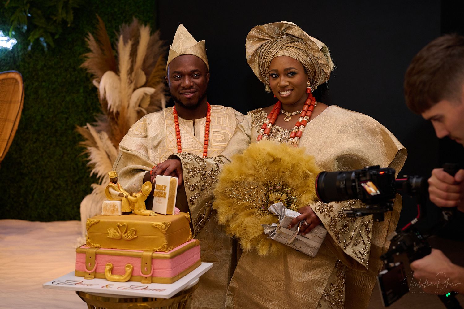 Nigerian wedding couple posing with their decorative cake while photographer captures the moment.