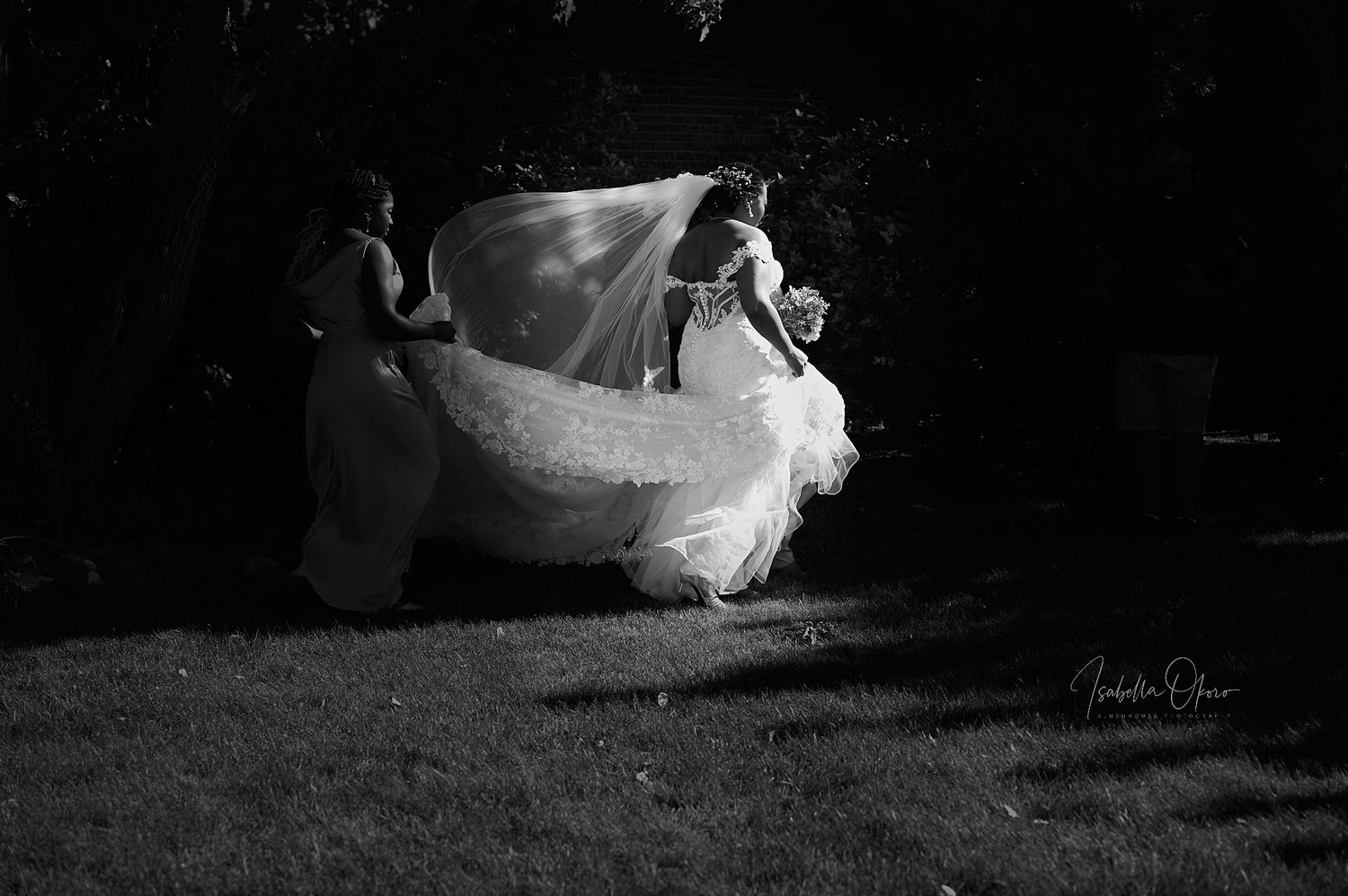 A dramatic black and white photo of a bride's dress flowing in the wind during an outdoor photoshoot.