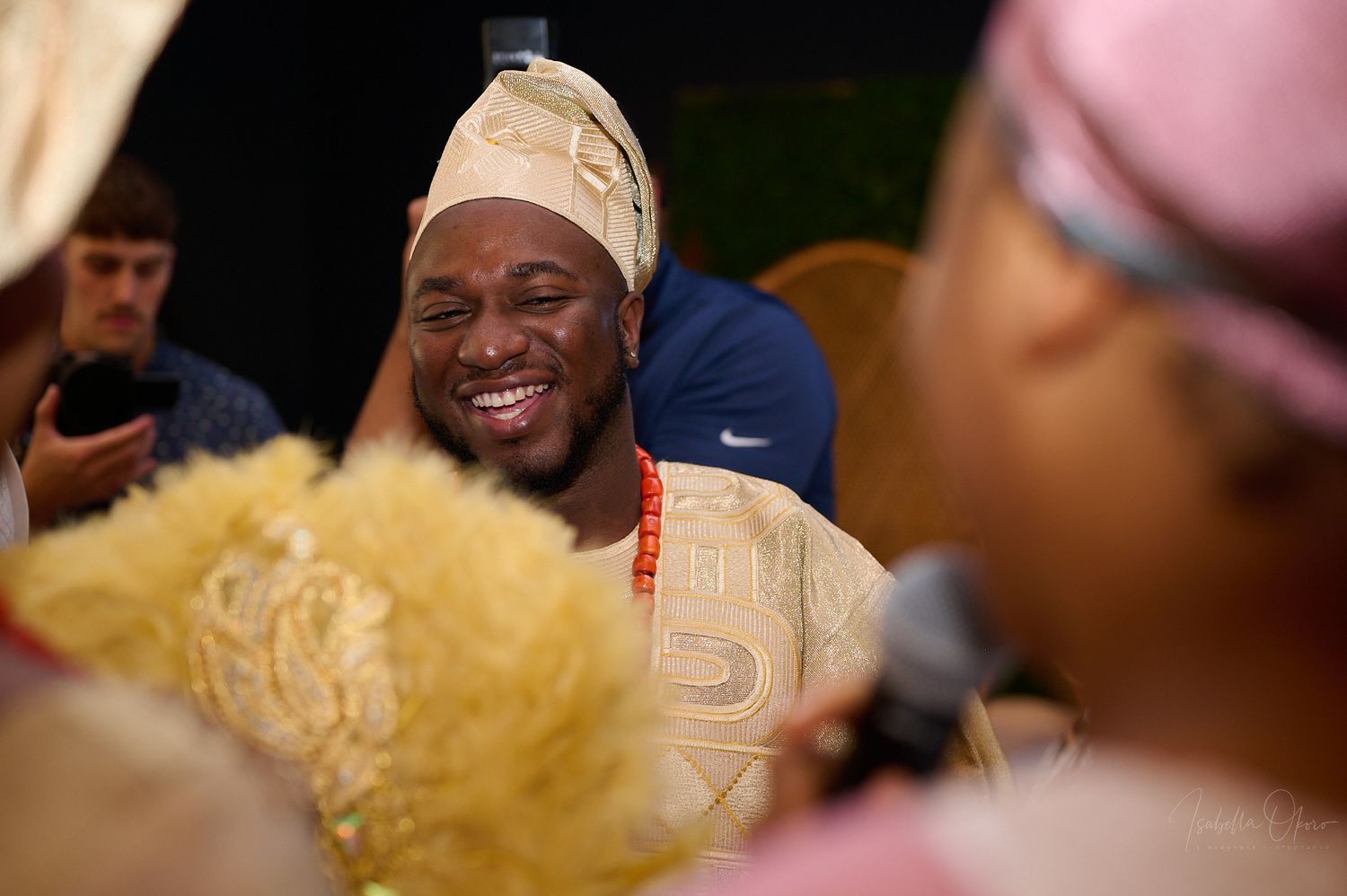 Wedding guest wearing traditional African cap and attire smiles during celebration.