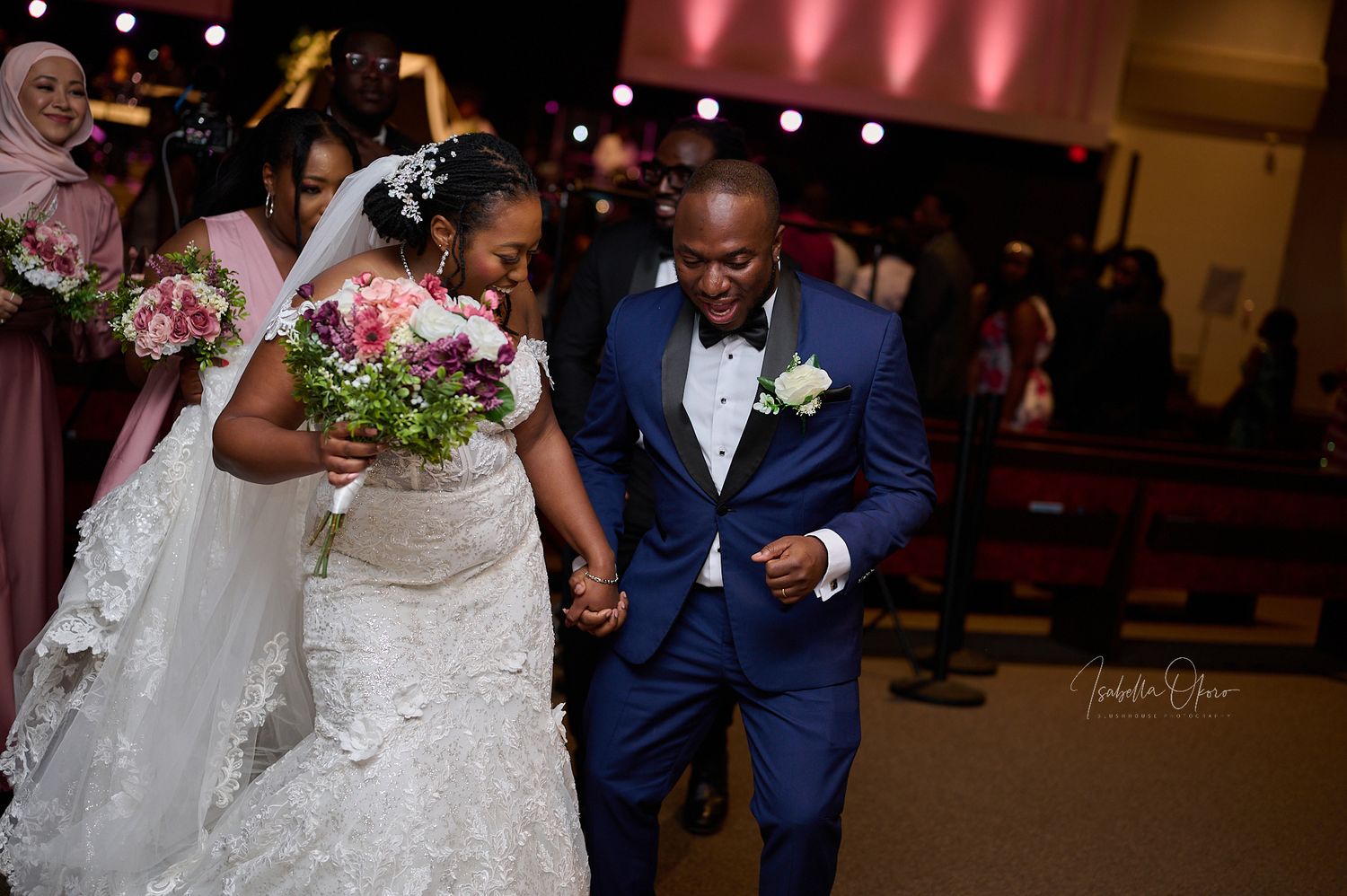 Wedding couple making their exit through church aisle with pink floral accents.