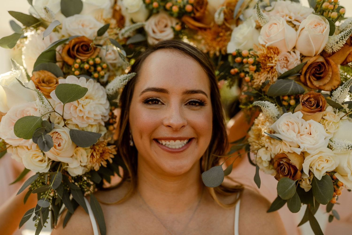 Close-up of peach and white wedding bouquets with eucalyptus leaves and roses.