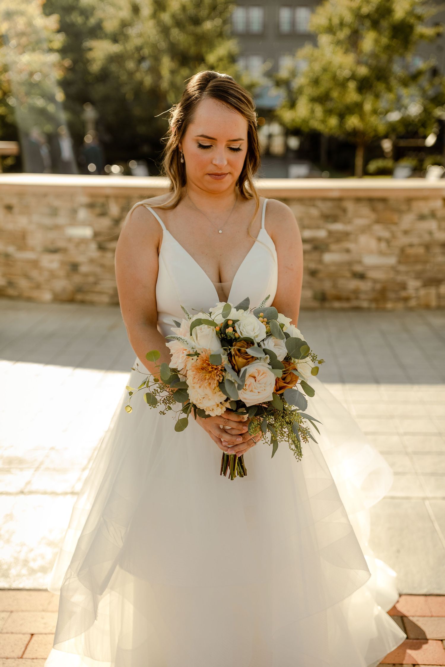 White ballgown wedding dress with floral bouquet in golden sunlight.