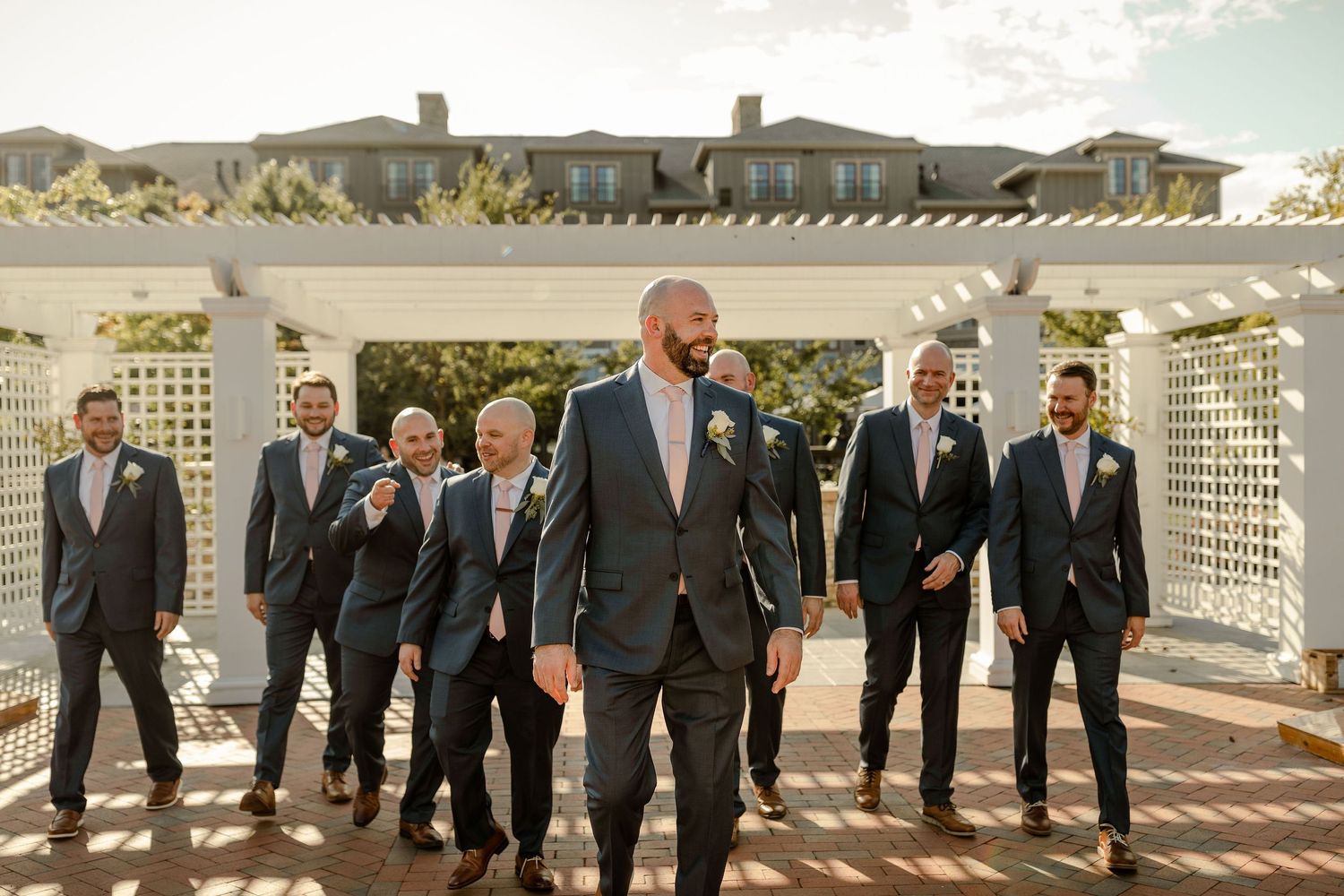 Wedding party lined up on outdoor patio with white lattice and water view in background.