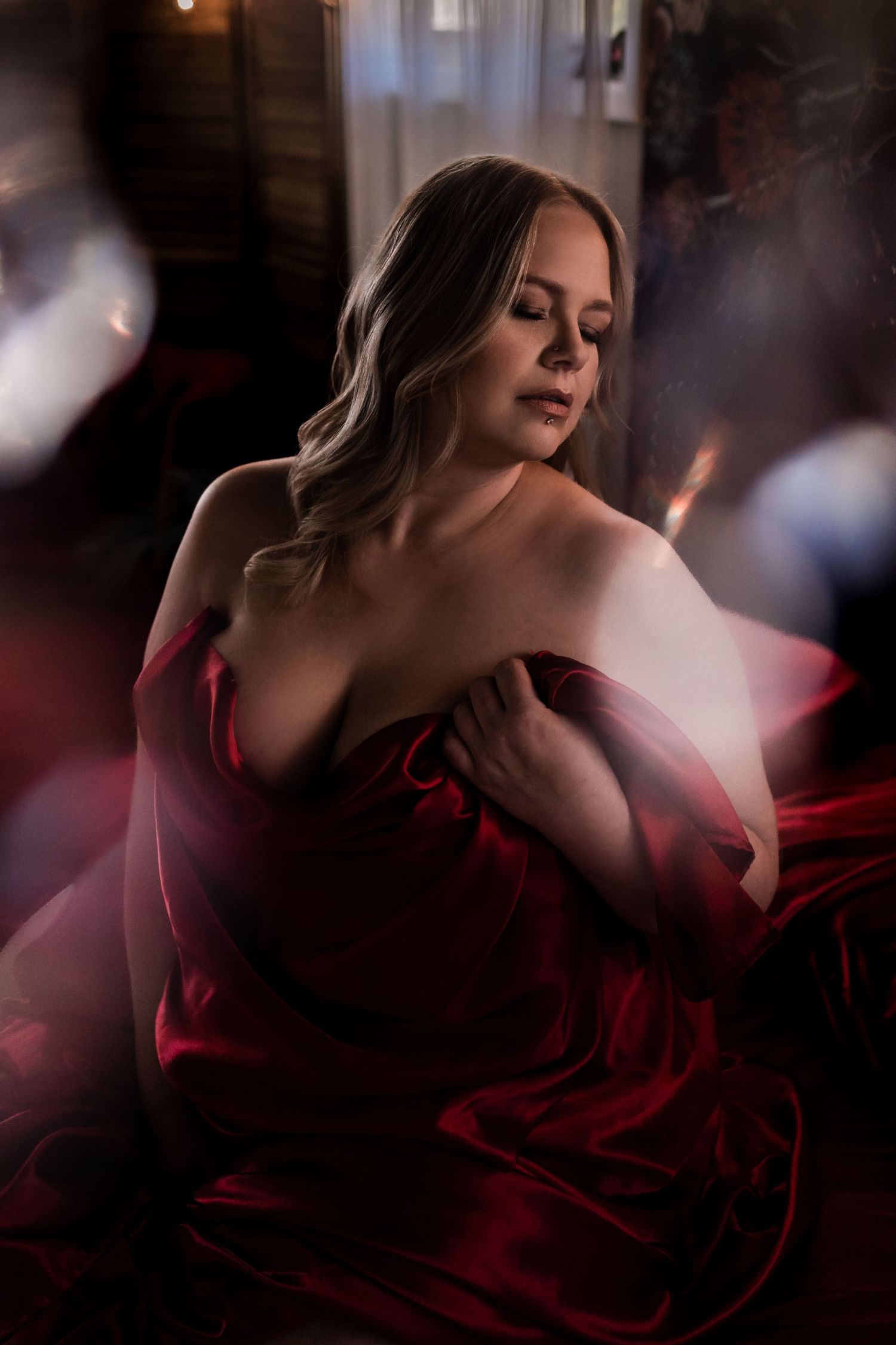 Romantic boudoir photography with red fabric and soft, dreamy lighting effects.