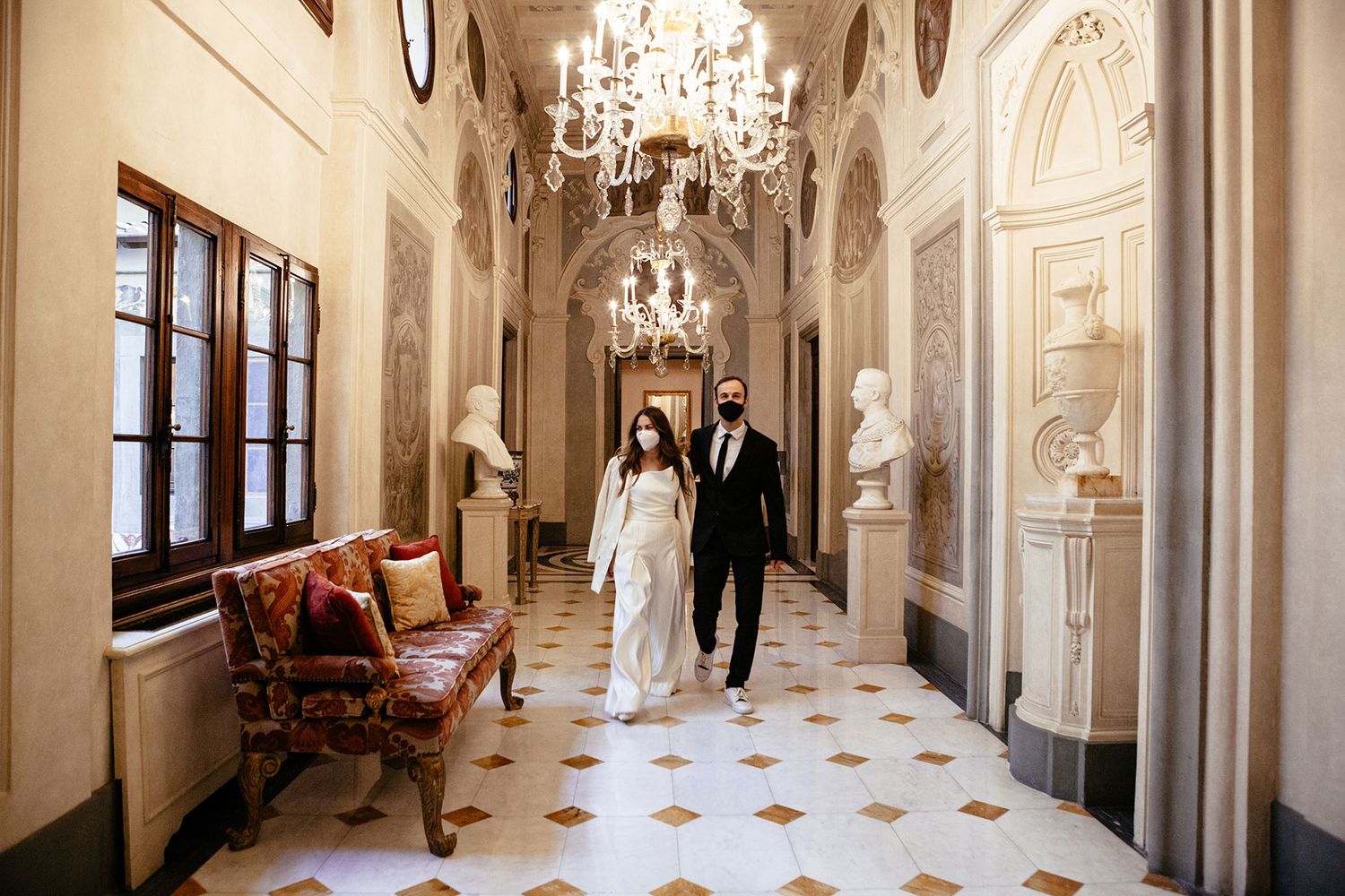 bride and groom in face masks walk down the hallway at the Four Seasons Hotel in Florence after their lockdown elopement