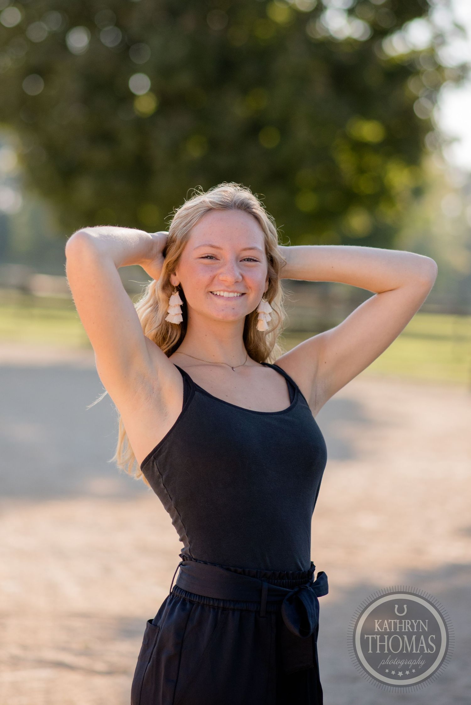 Summer portrait in black dress against blurred natural background.