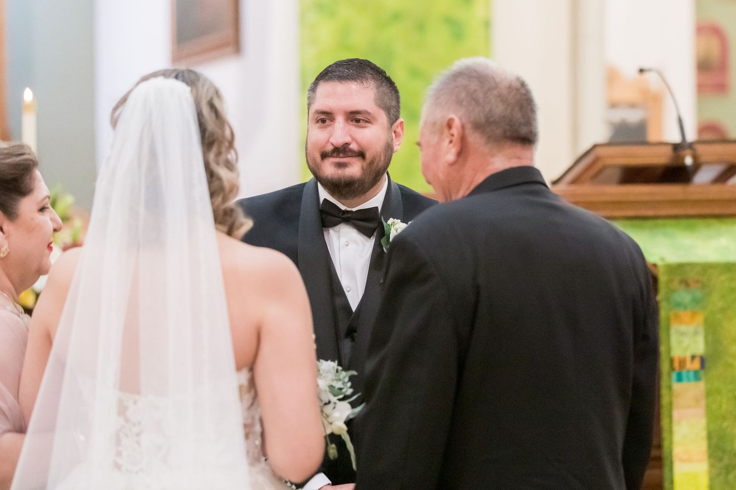 Wedding ceremony in progress at ornate church altar with couple and officiant.