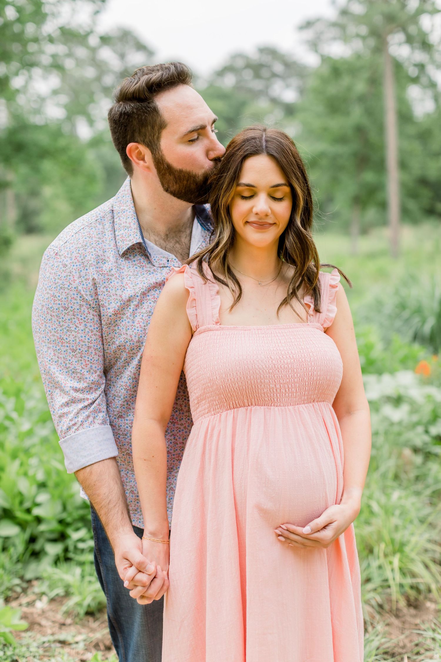 An intimate maternity portrait of a couple sharing a tender moment outdoors.