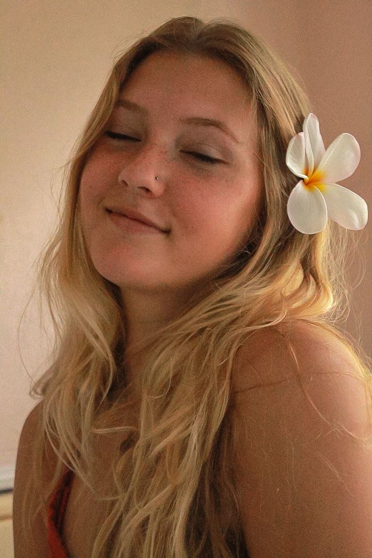 A girl smiles with a flower in her hair during an editorial photo session