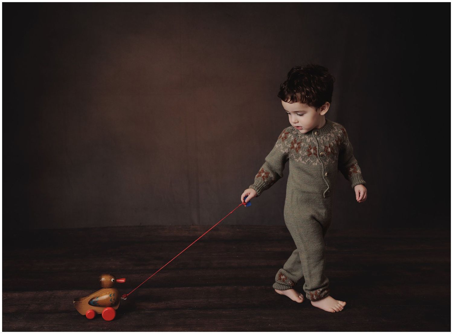 Toddler boy walking and pulling wooden toy during milestone portrait session photographed by Austin child photographer
