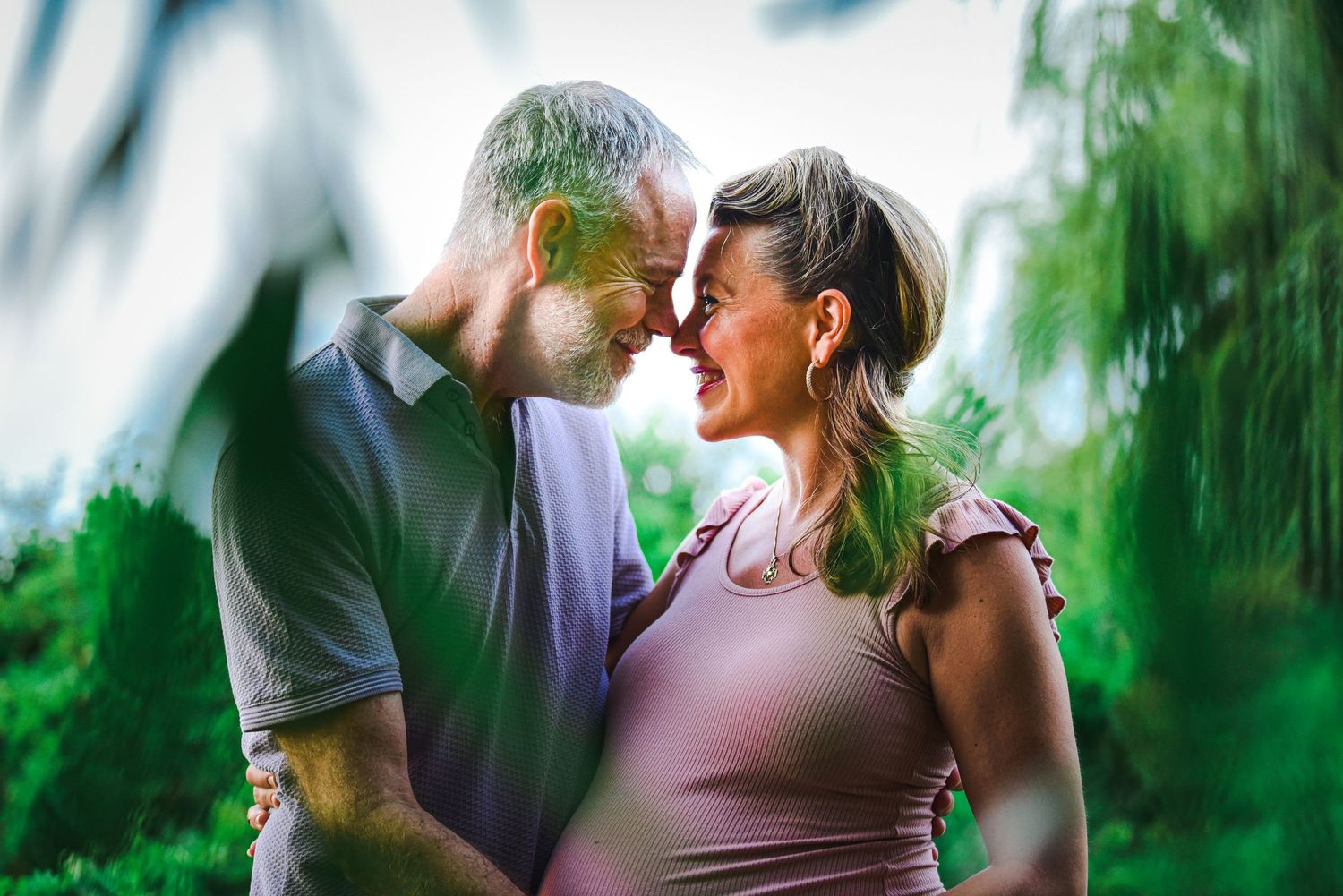 Romantic couple embracing outdoors in a natural green setting.