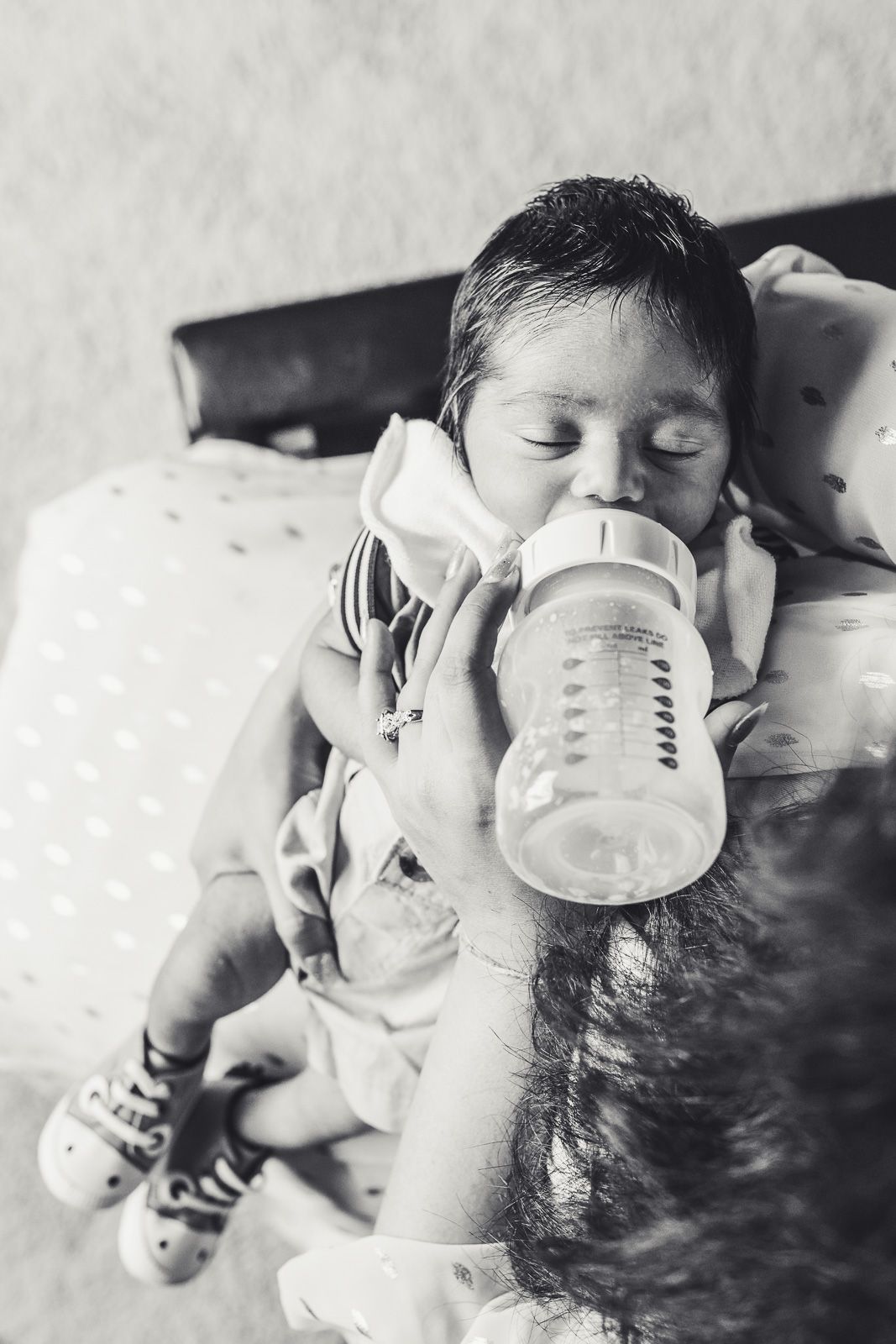 Black and white photo of mother feeding a bottle to newborn baby boy