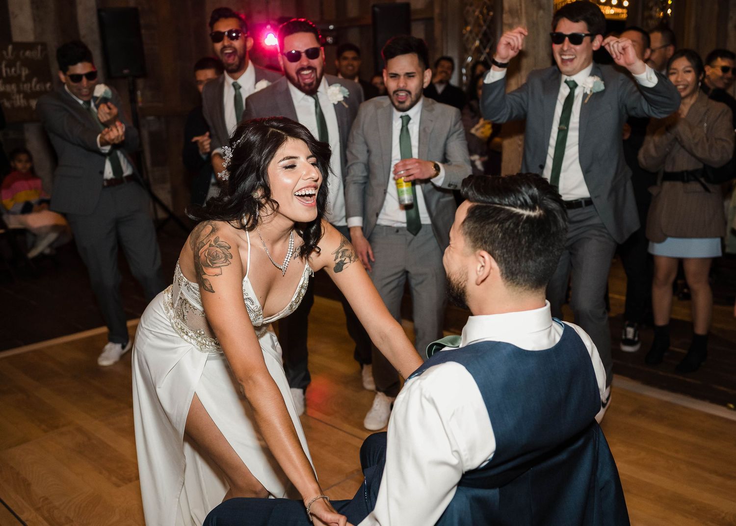 Couple dancing together at a wedding reception while guests cheer and celebrate on the dance floor.