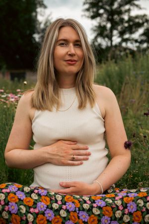 zwangere vrouw zit in een bloemenveld
