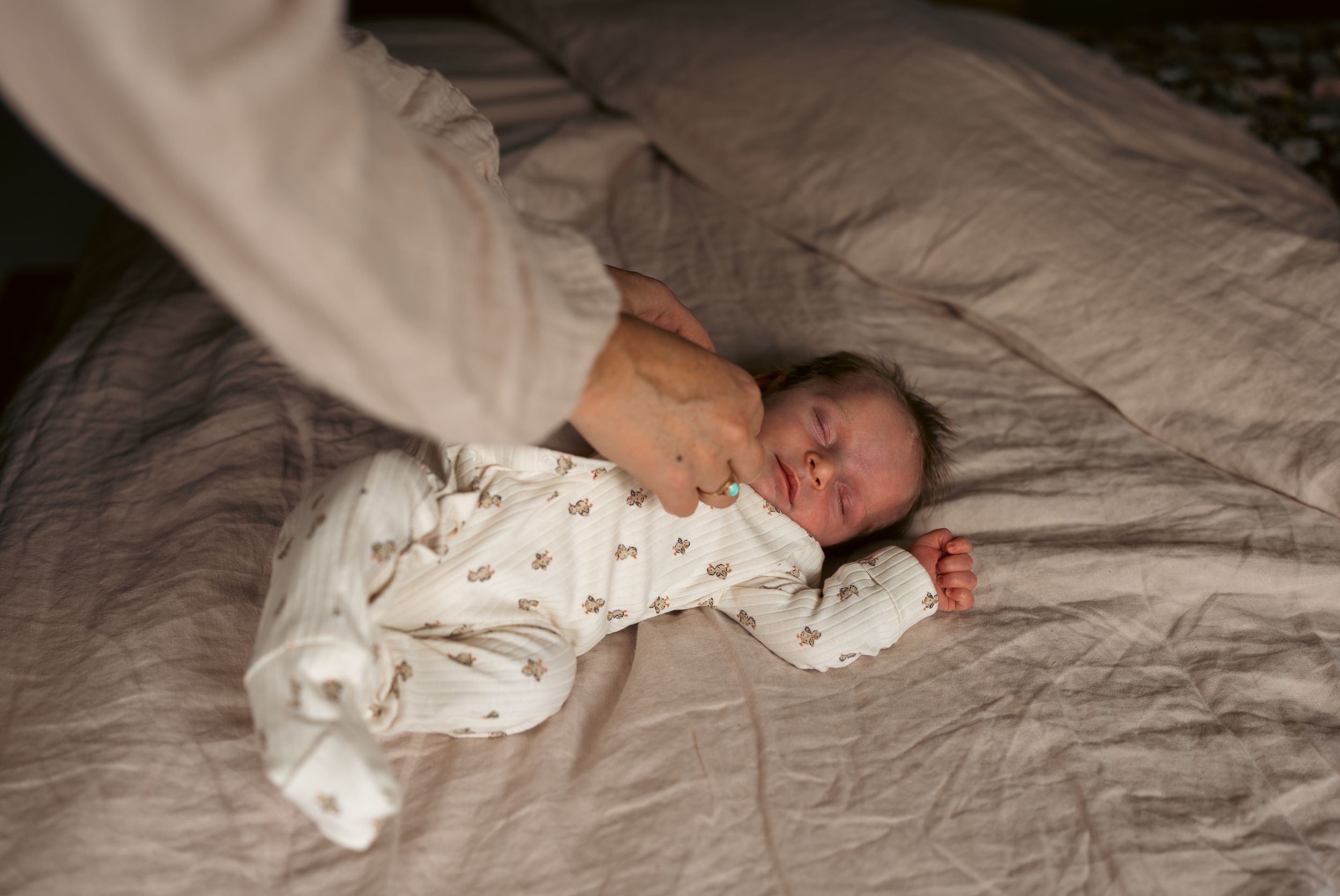 slapende baby wordt aangekleed op bed