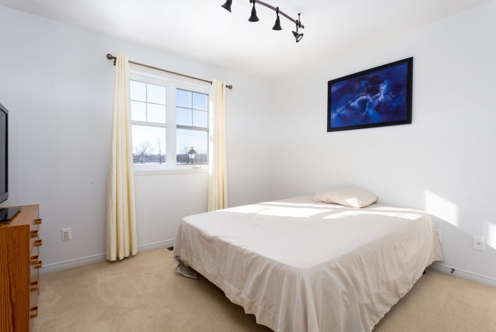 Sunlight bedroom with carpeted floors. Taken by professional real estate photographer.