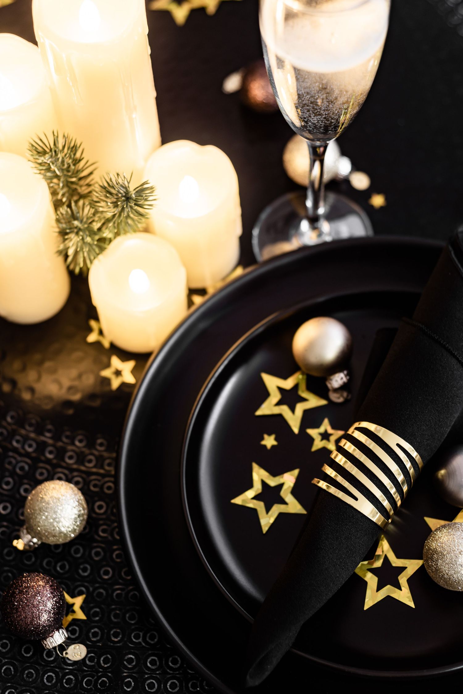 close up of dinner set up for party, with confetti and napkins, candles, black, stylish