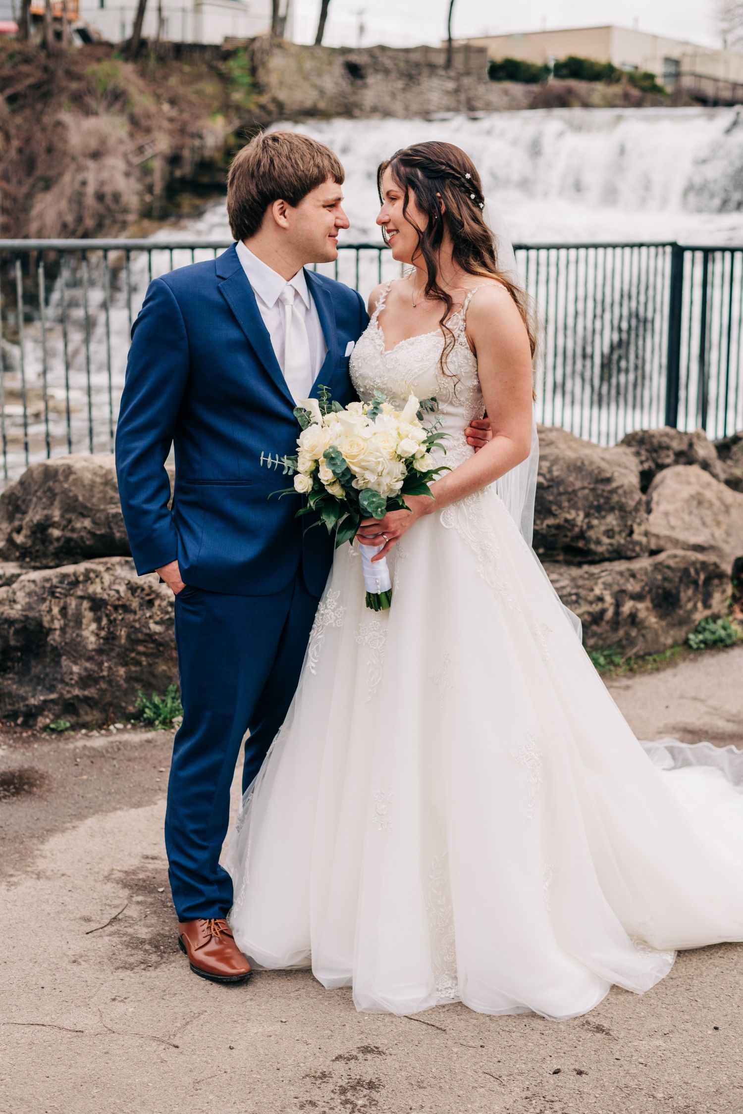 bride and groom in front of a waterfall on their wedding day