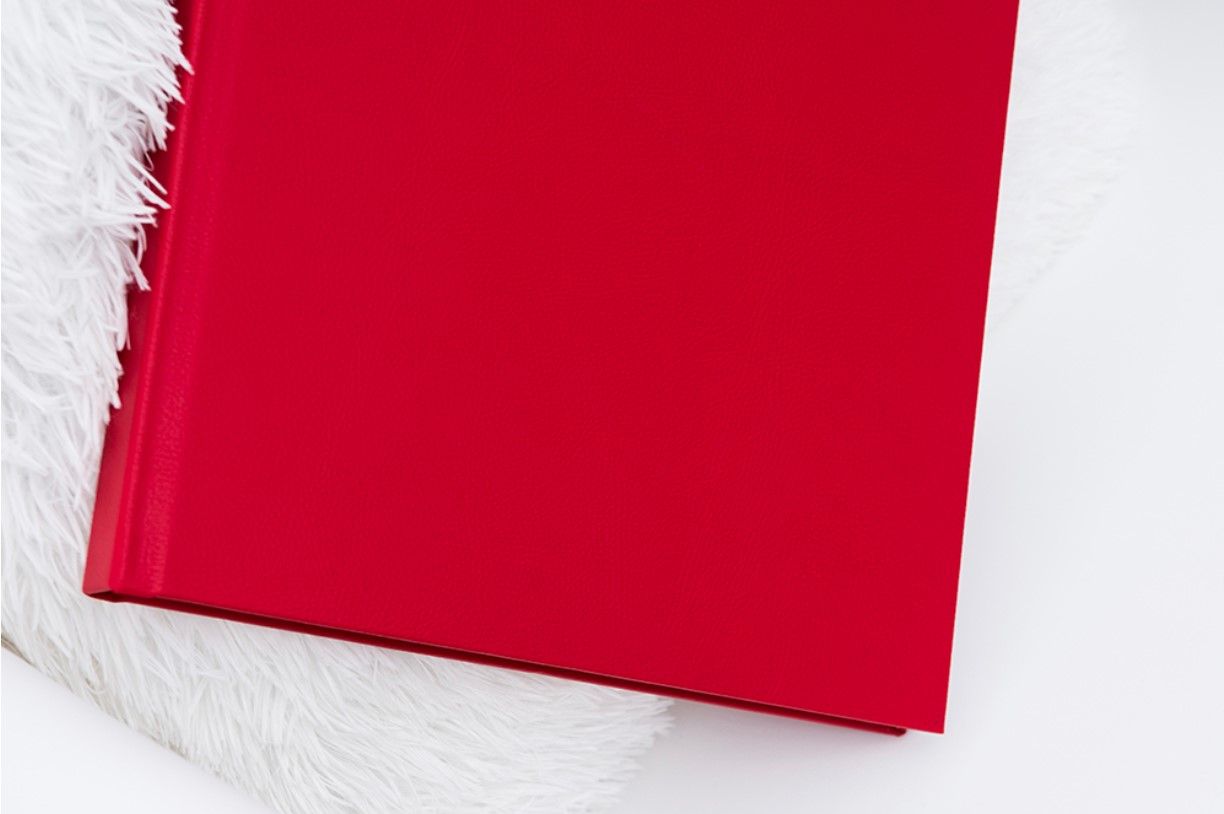 Bright red photo album cover displayed on white textured background.