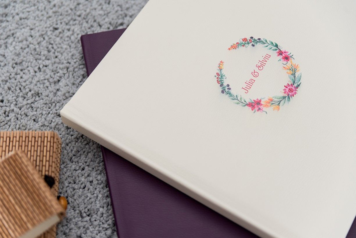 Stack of soft pastel books with floral wreath design on white cover.