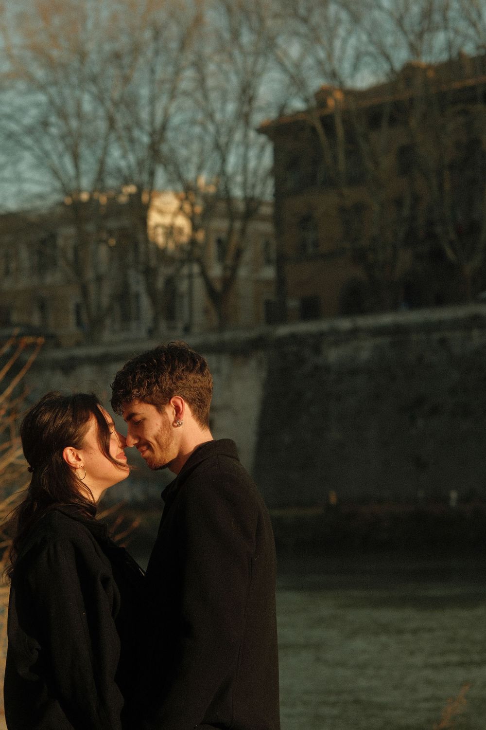 A romantic sunset moment between a couple near historic stone buildings.