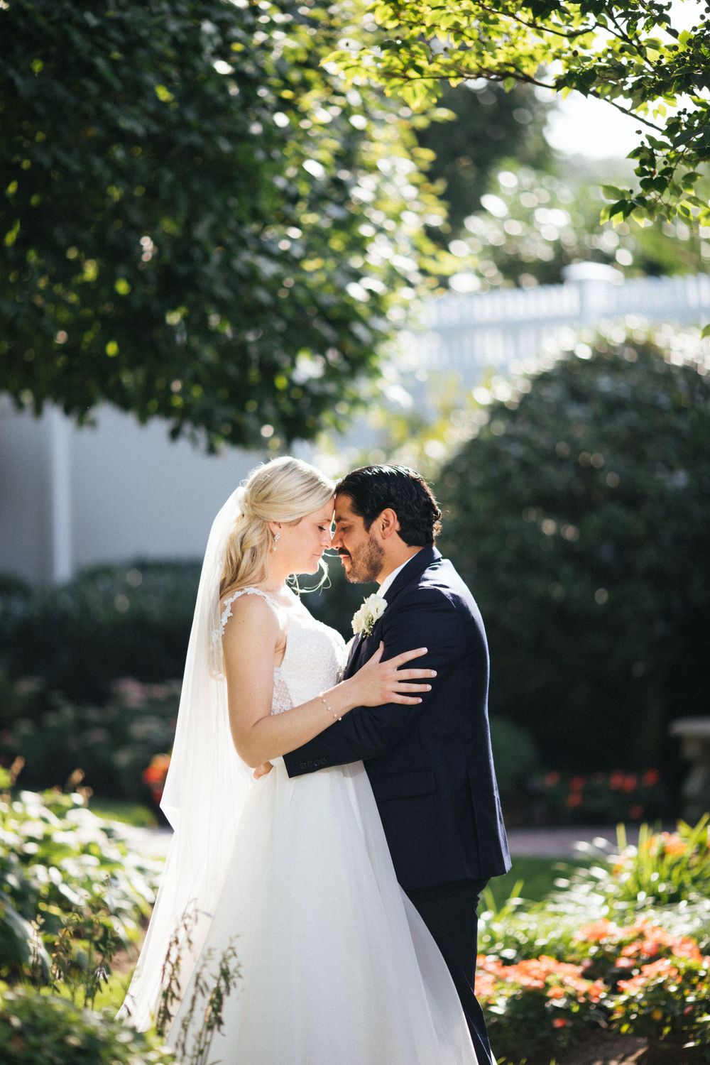A tender moment between newlyweds in a sunny garden setting.