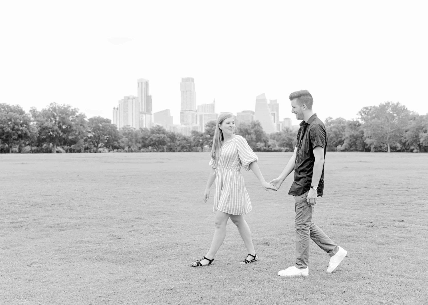 A black and white photo of a couple walking together in a city park.