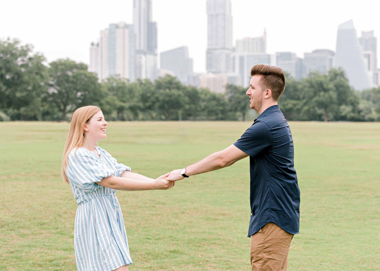 Dancing together in a scenic park with downtown skyscrapers creating a stunning backdrop.