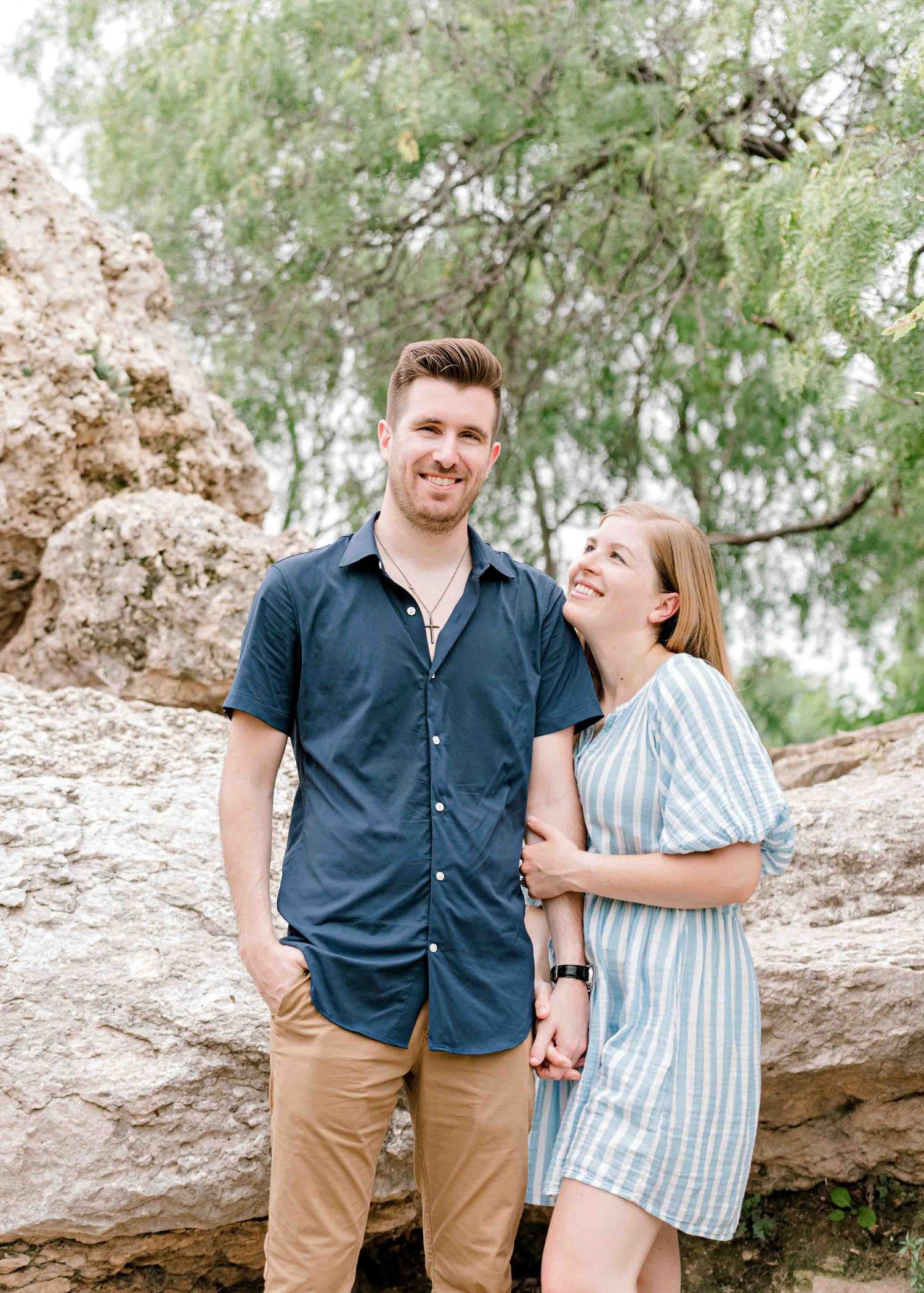 A joyful moment shared between a couple against a backdrop of willow trees.