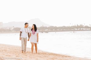 A romantic couple walking barefoot on a tropical beach at sunset.