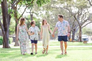 A family takes a carefree walk together through a green park wearing coordinated floral outfits.