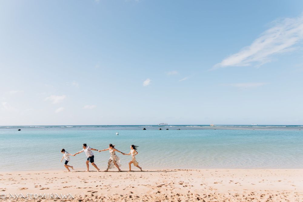 Four silhouettes walk hand in hand along a pristine turquoise beach.