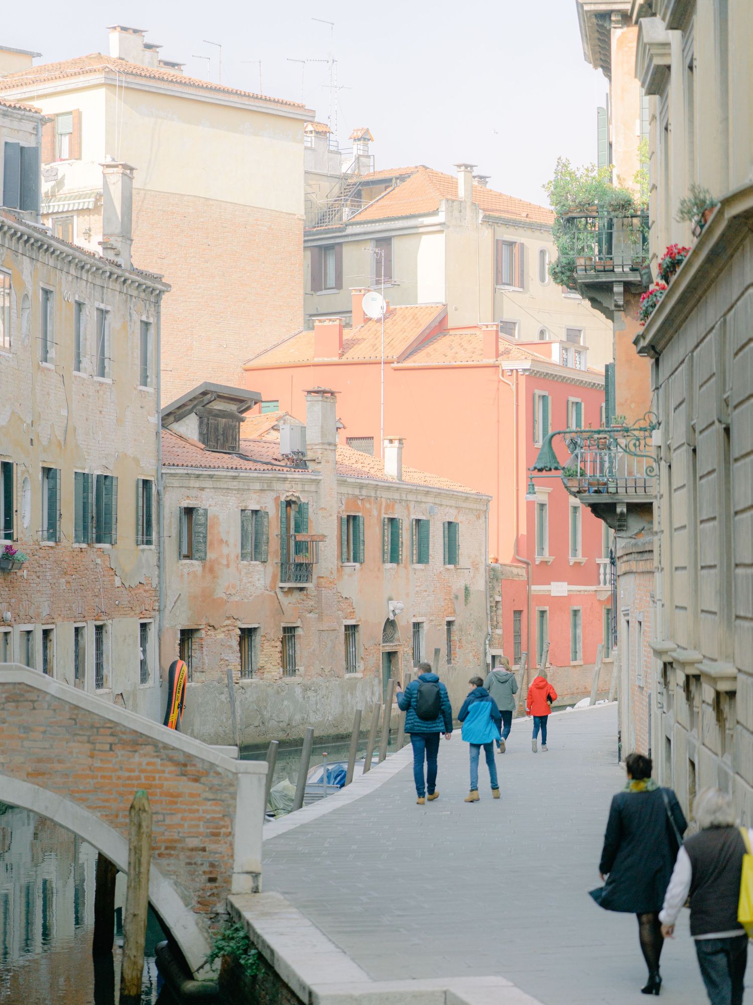 People walking next to a canal in the streets of Venice Italy