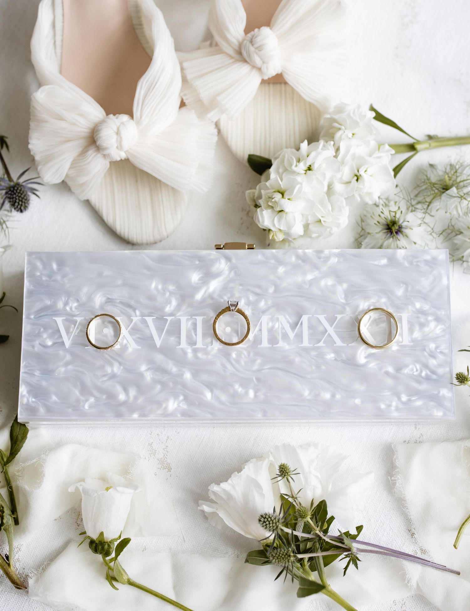 Wedding invitation suite with white floral elements and delicate details on a light background.