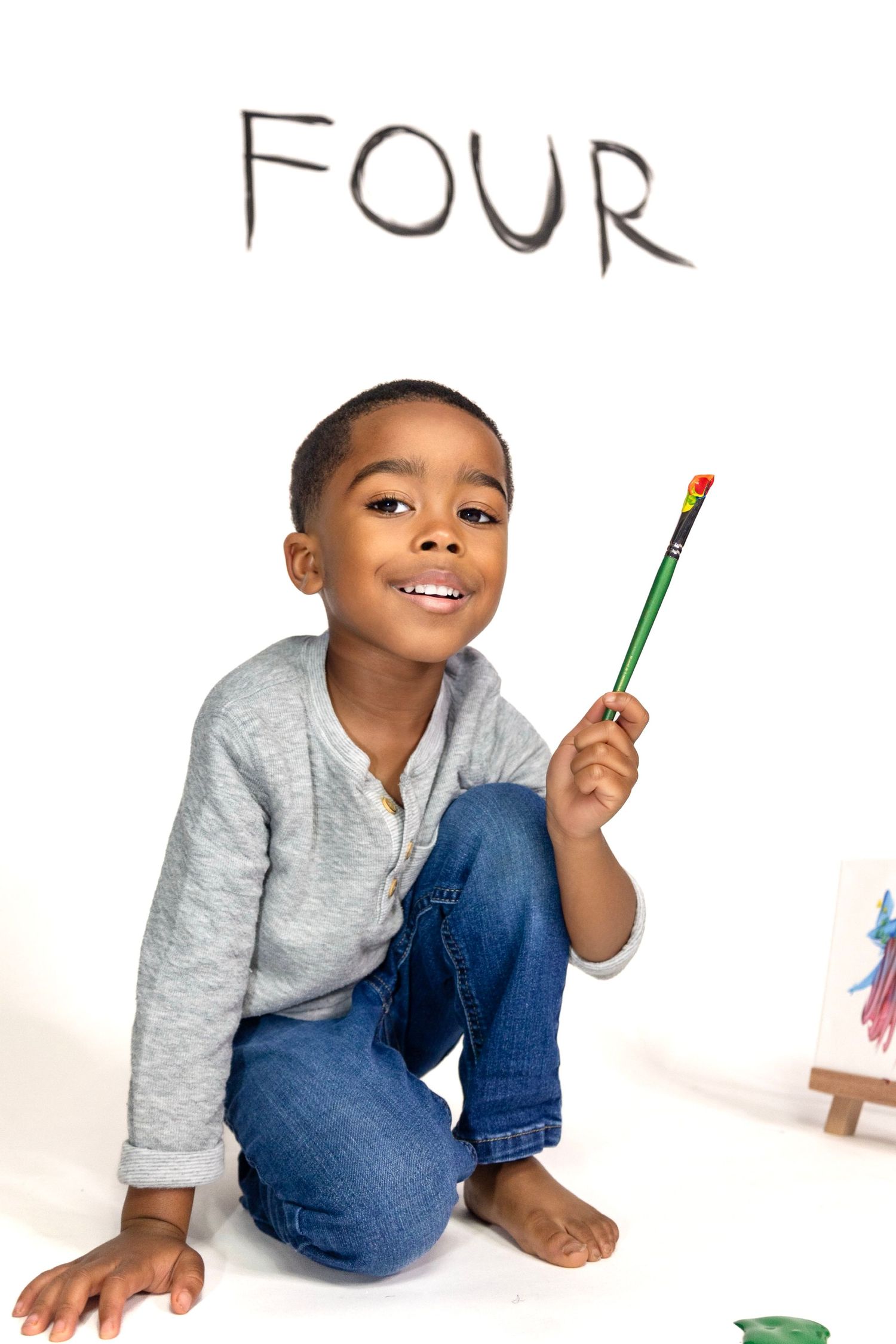 Young student holding a pencil with the word 'FOUR' written above in a classroom setting.