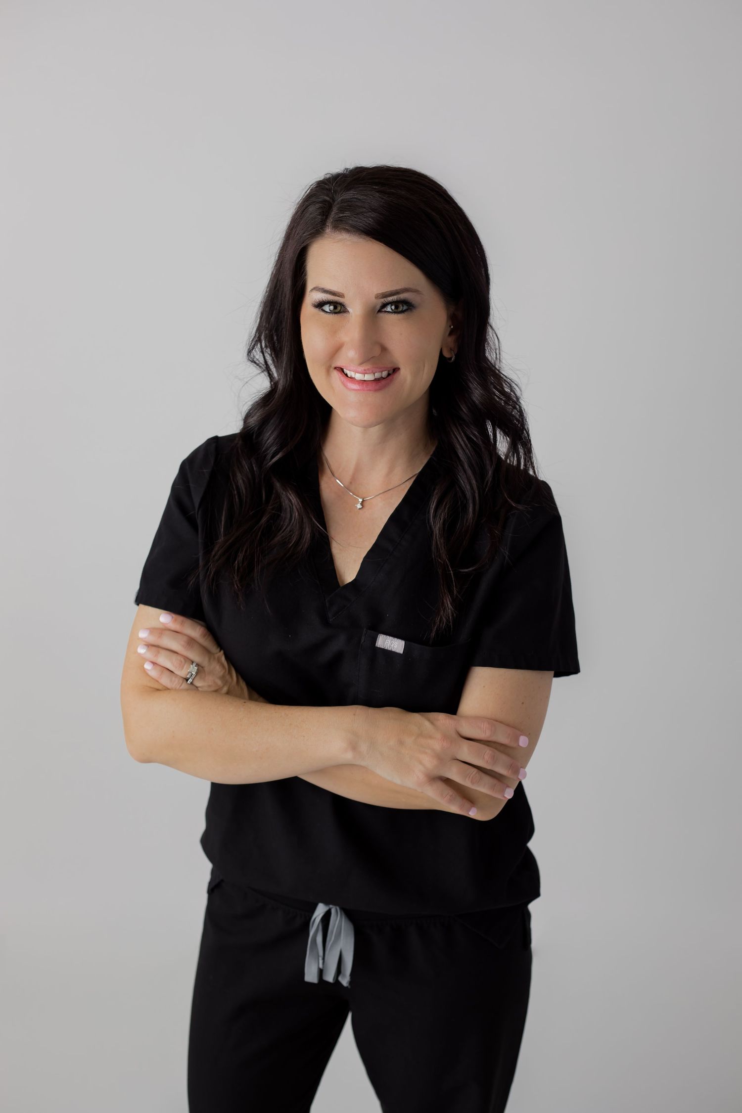 Headshot of a nurse wearing scrubs on a simple white background for her branding portrait session at a studio.