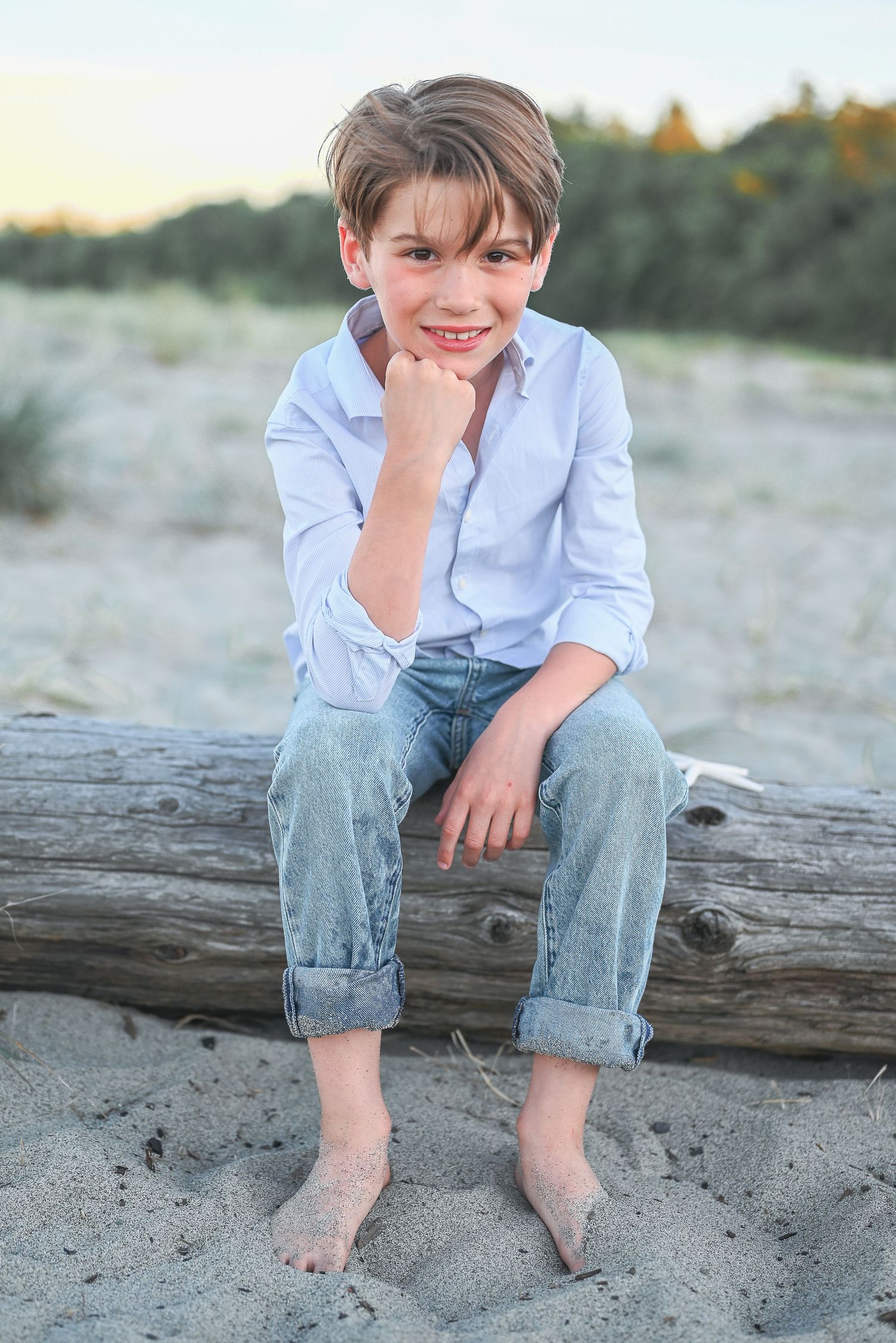 Young boy at the beach in jeans and dress shirt.