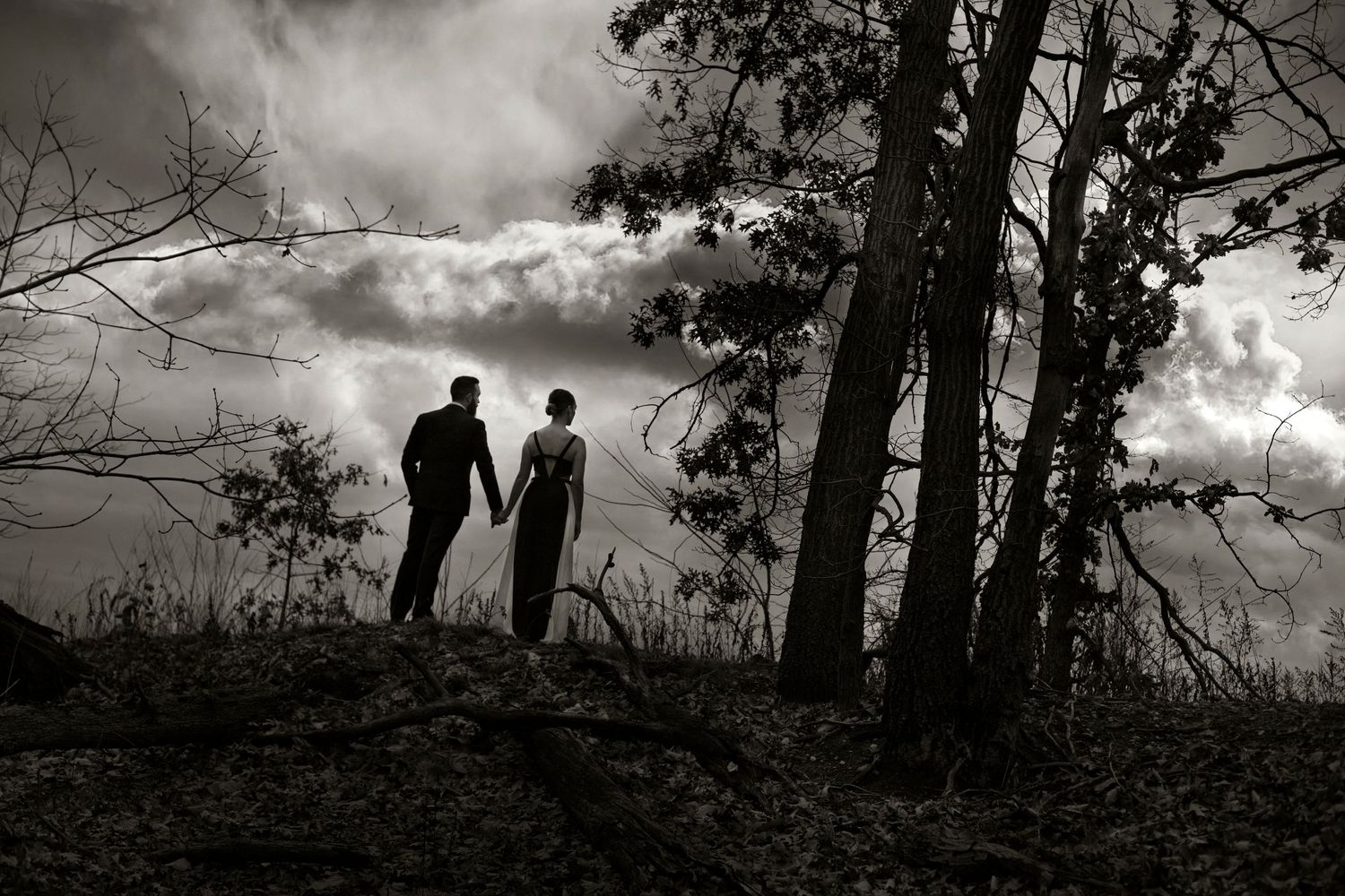 a black and white photograph of the couple standing in the woods, in the style of elegant cityscapes