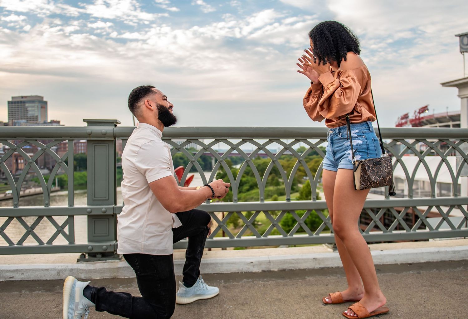 A romantic proposal moment captured along a waterfront walkway during sunset.