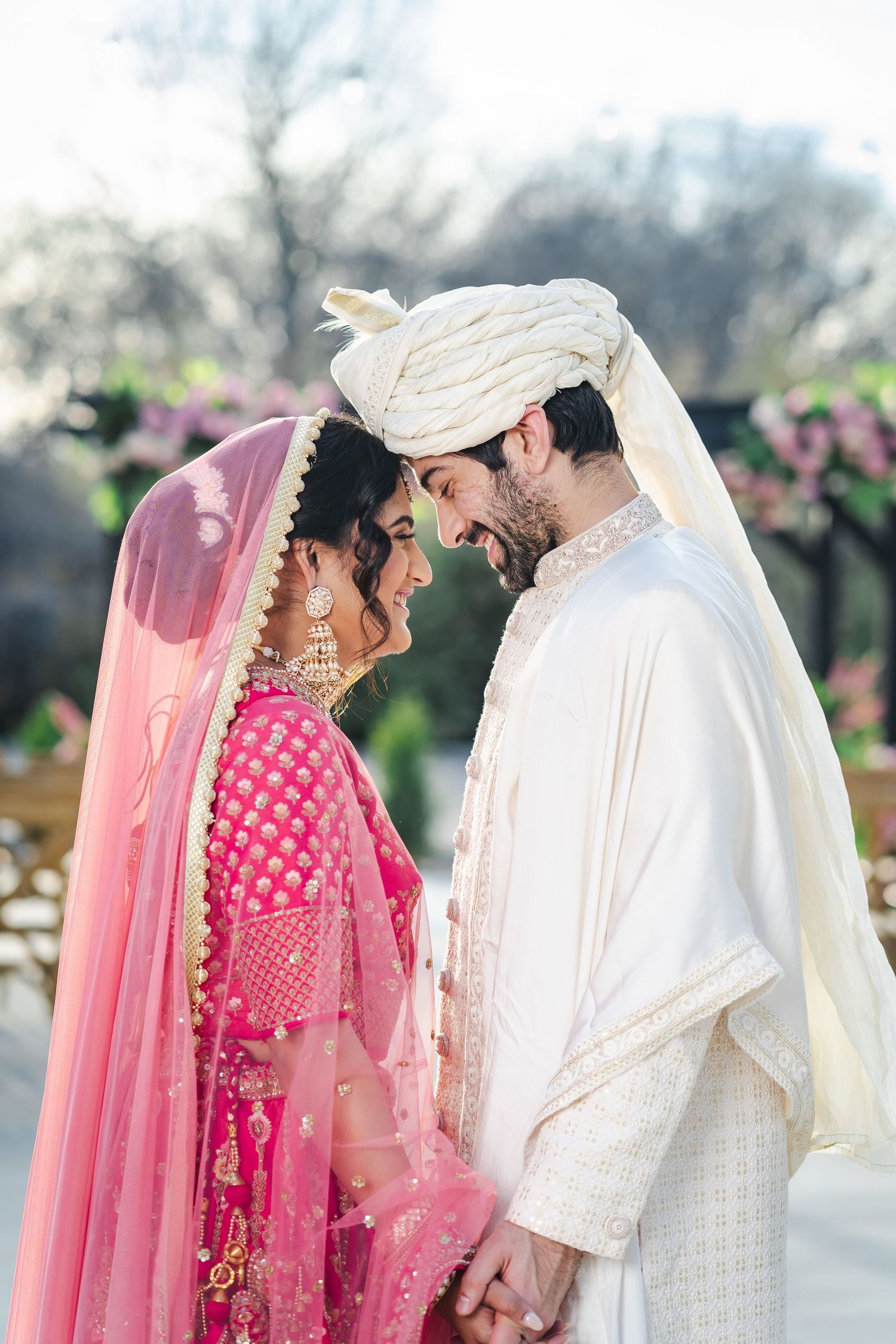 A couple in traditional South Asian wedding attire sharing an intimate moment outdoors.