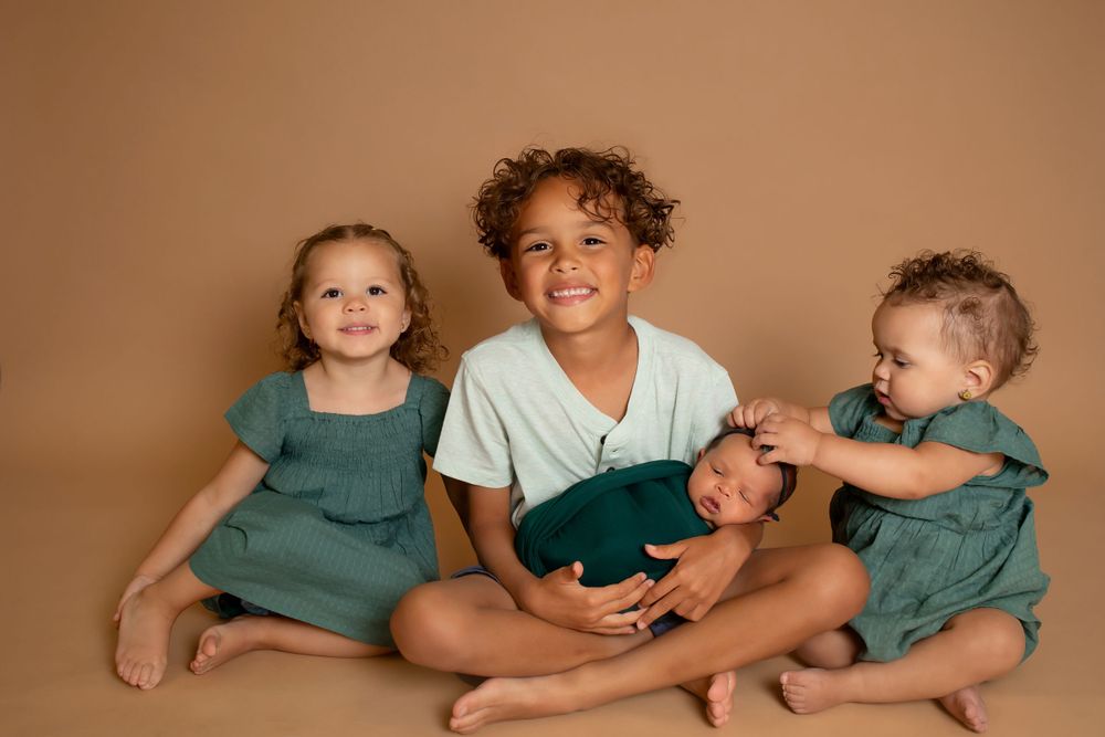 Siblings in coordinated outfits sharing playful moment on brown backdrop.