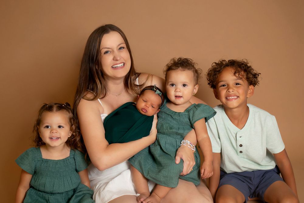 Family portrait against brown backdrop with children in coordinating outfits.
