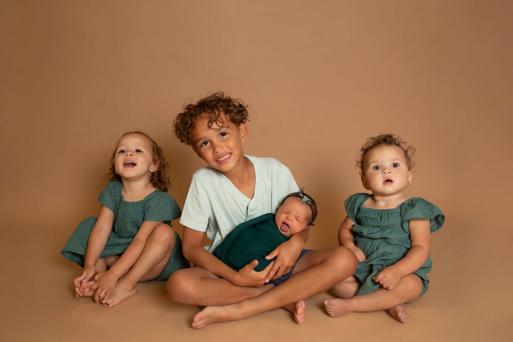 Candid moment of siblings laughing and smiling against neutral brown backdrop.
